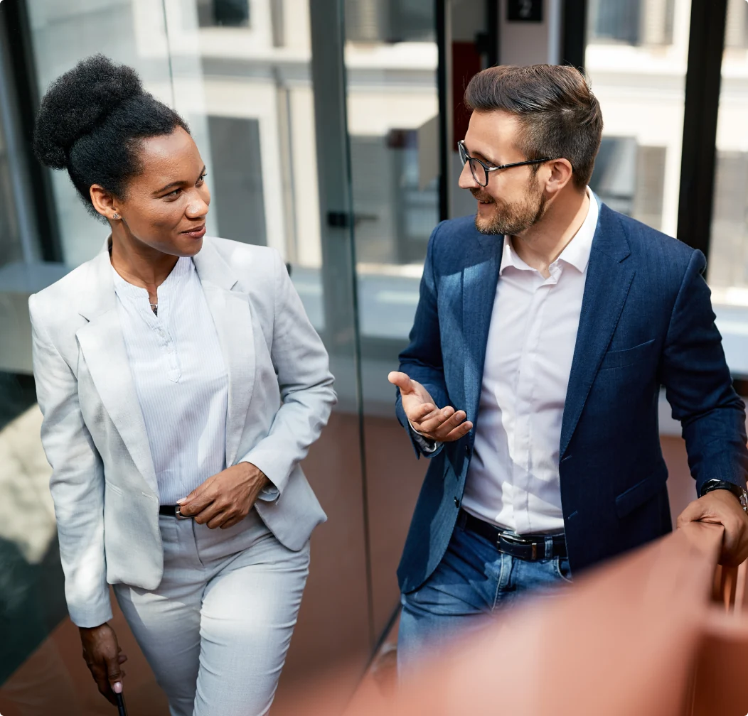 A man in a suit speaks with a woman in a suit.